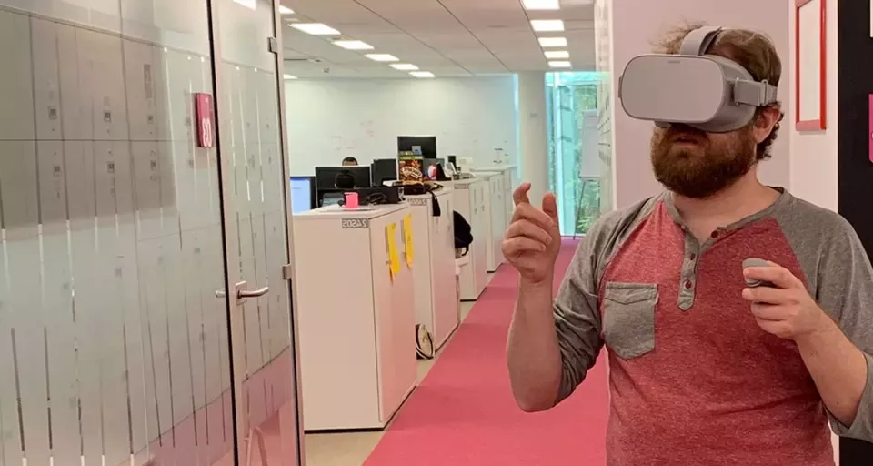 A man in an office wearing a virtual reality headset, engaged in an immersive digital experience.