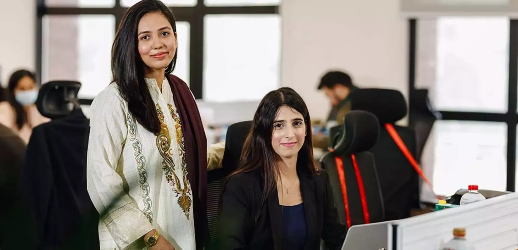  Two women in front of a computer, collaborating and sharing ideas as they work together.