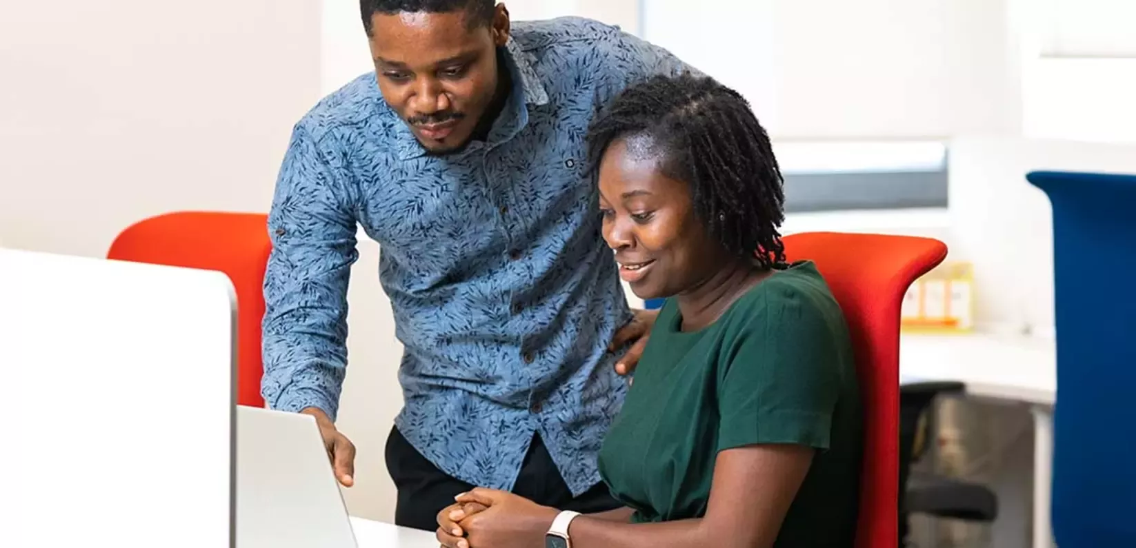 A man and woman are focused on a laptop screen, engaged in discussion or collaboration.