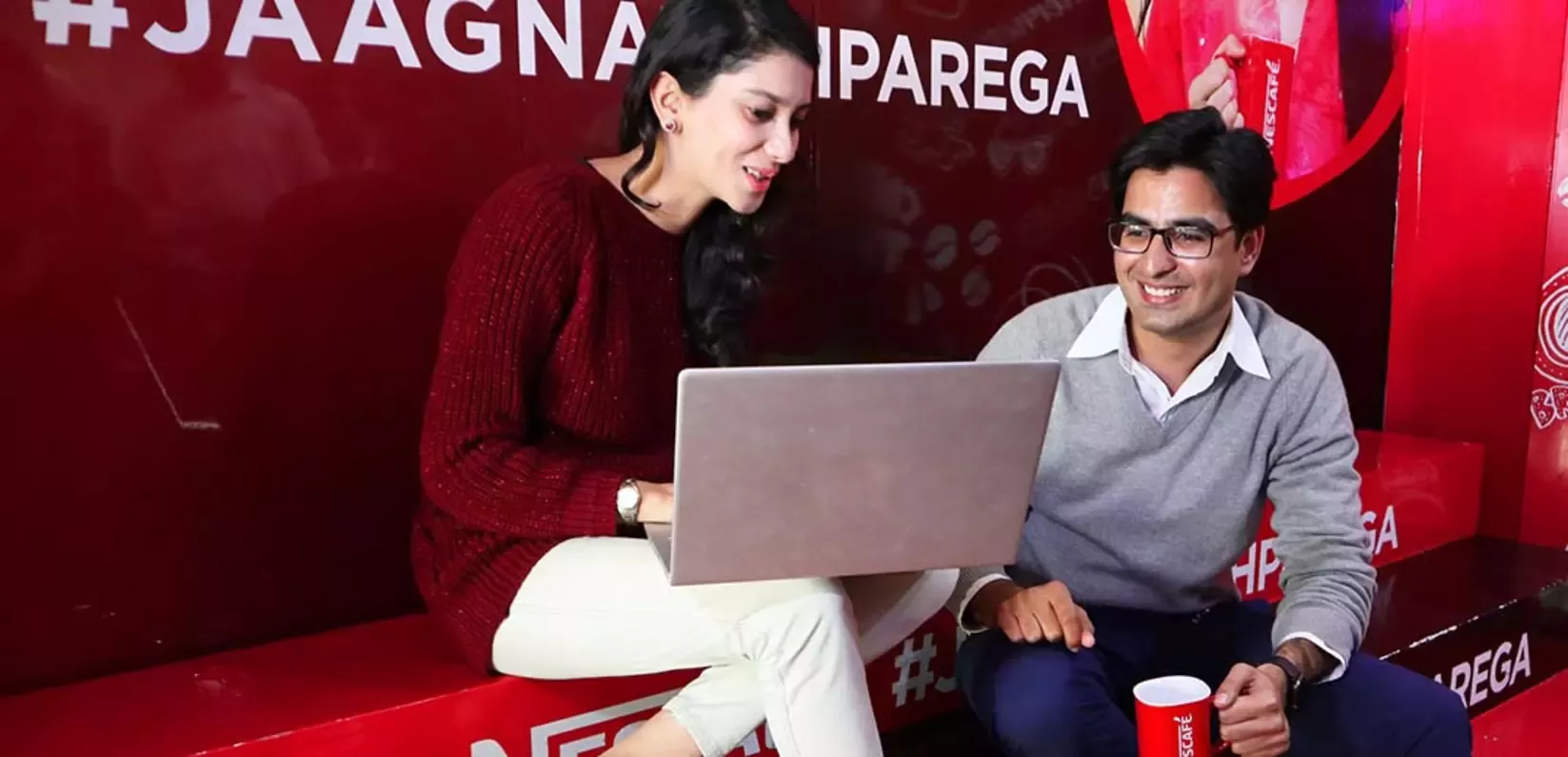 A man and woman sit beside each other, using a laptop for work